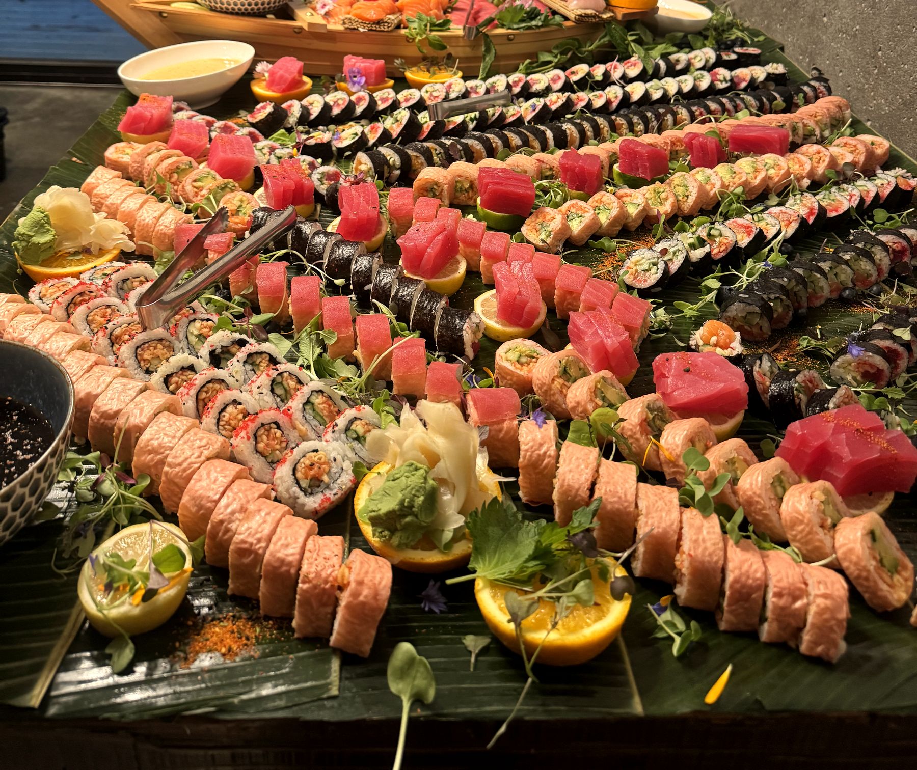 Gros plan sur une table Sushika: rolls au saumon, thon et agrumes sur feuille de bananier